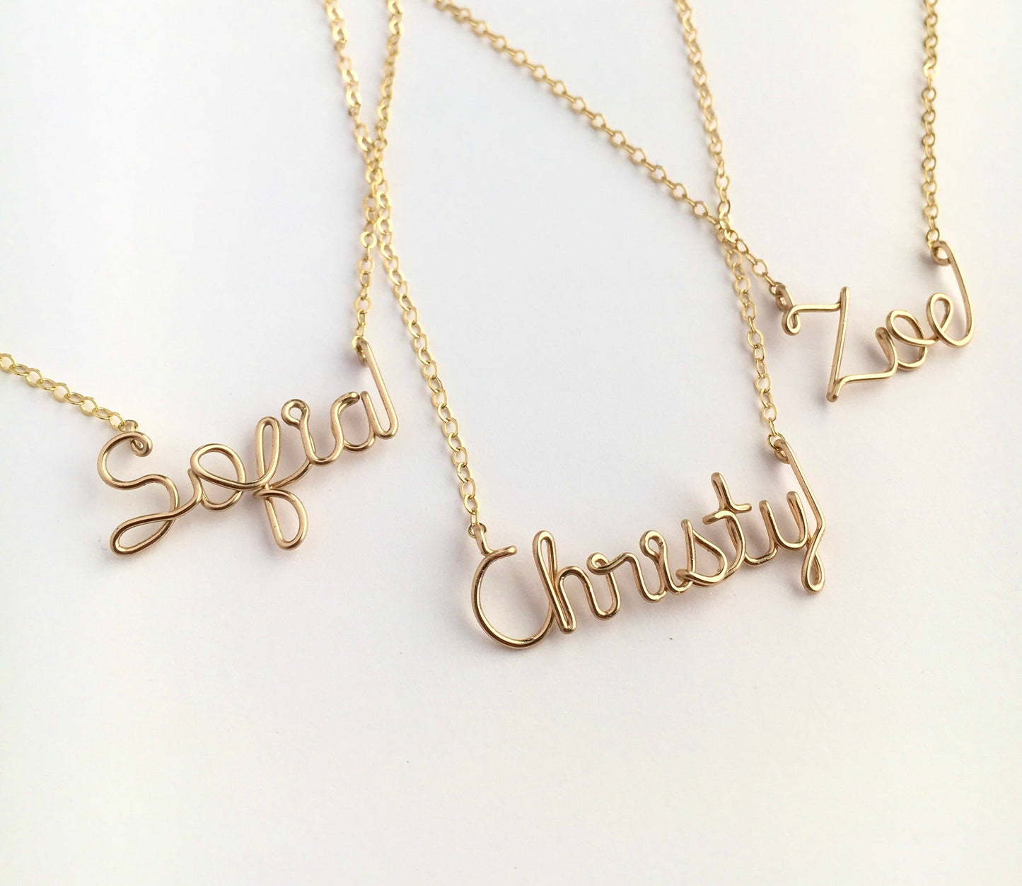 Gold name necklaces on a white background