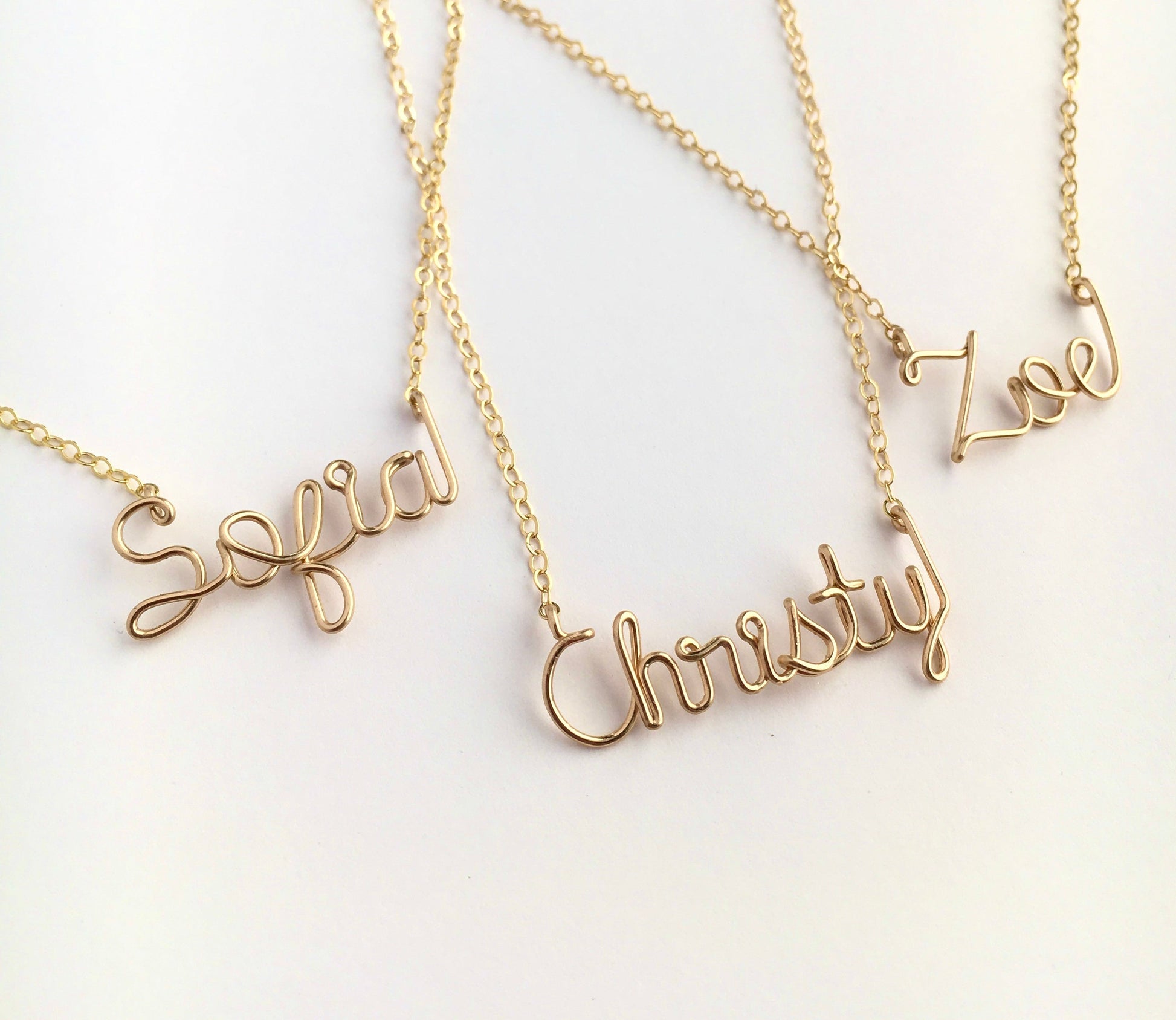Gold name necklaces on a white background