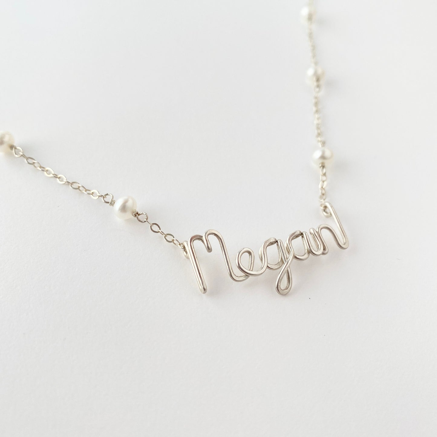 Name Necklace. Off White Freshwater Pearl Name Necklace in Sterling Silver. Script style font.